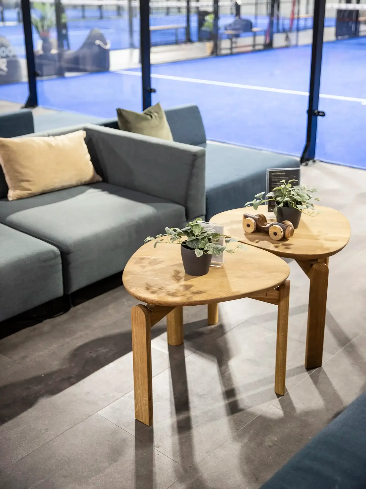 Oak side tables and blue fabric lounge sofas, designed for comfort and wear resistance in high-traffic sports environments.