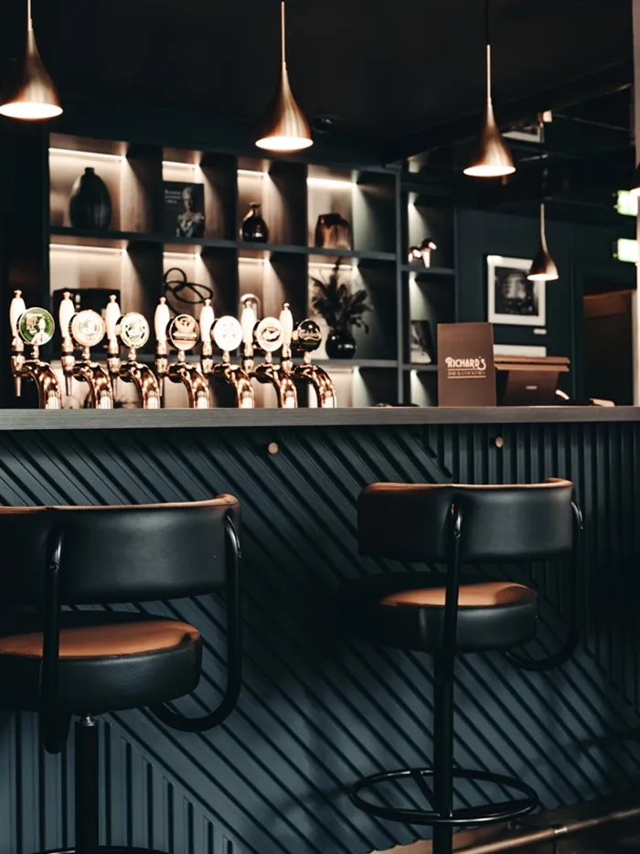 Modern bar design with chevron wood details and custom barstools in a high-end hospitality setting at Hotel Royal.