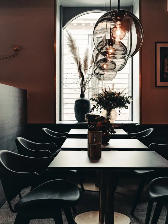 Dining area with sculptural glass pendant lights and bespoke tables for a contemporary restaurant interior at Richards Bar.