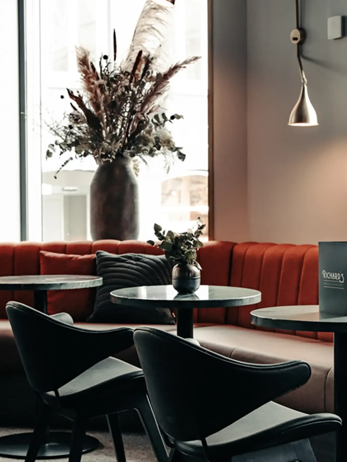 Custom bench seating in velvet with marble-top tables and elegant lighting at Richards Bar, Hotel Royal.