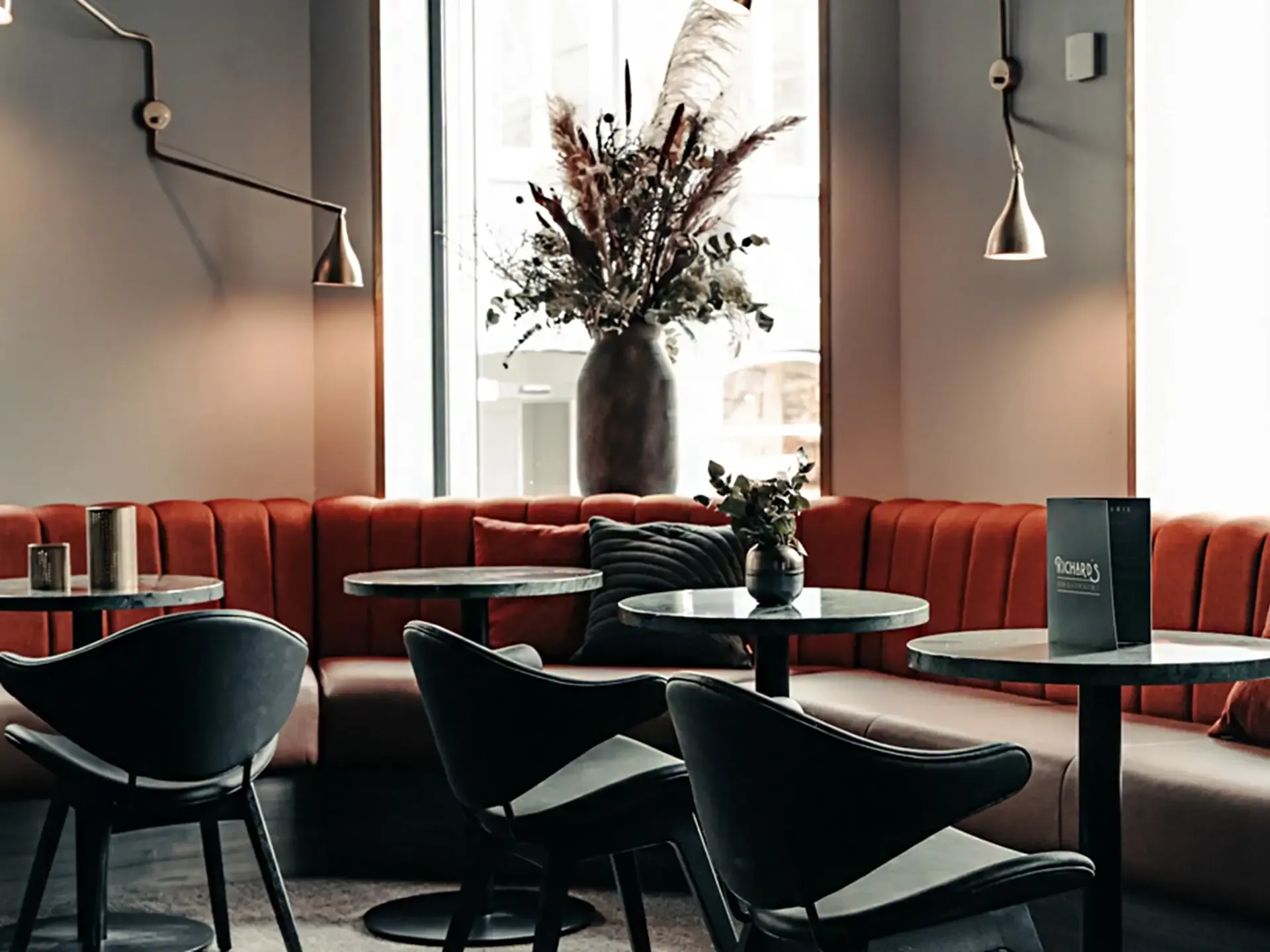 Velvet banquette seating paired with marble tables and bespoke chairs for a luxury restaurant at Hotel Royal.