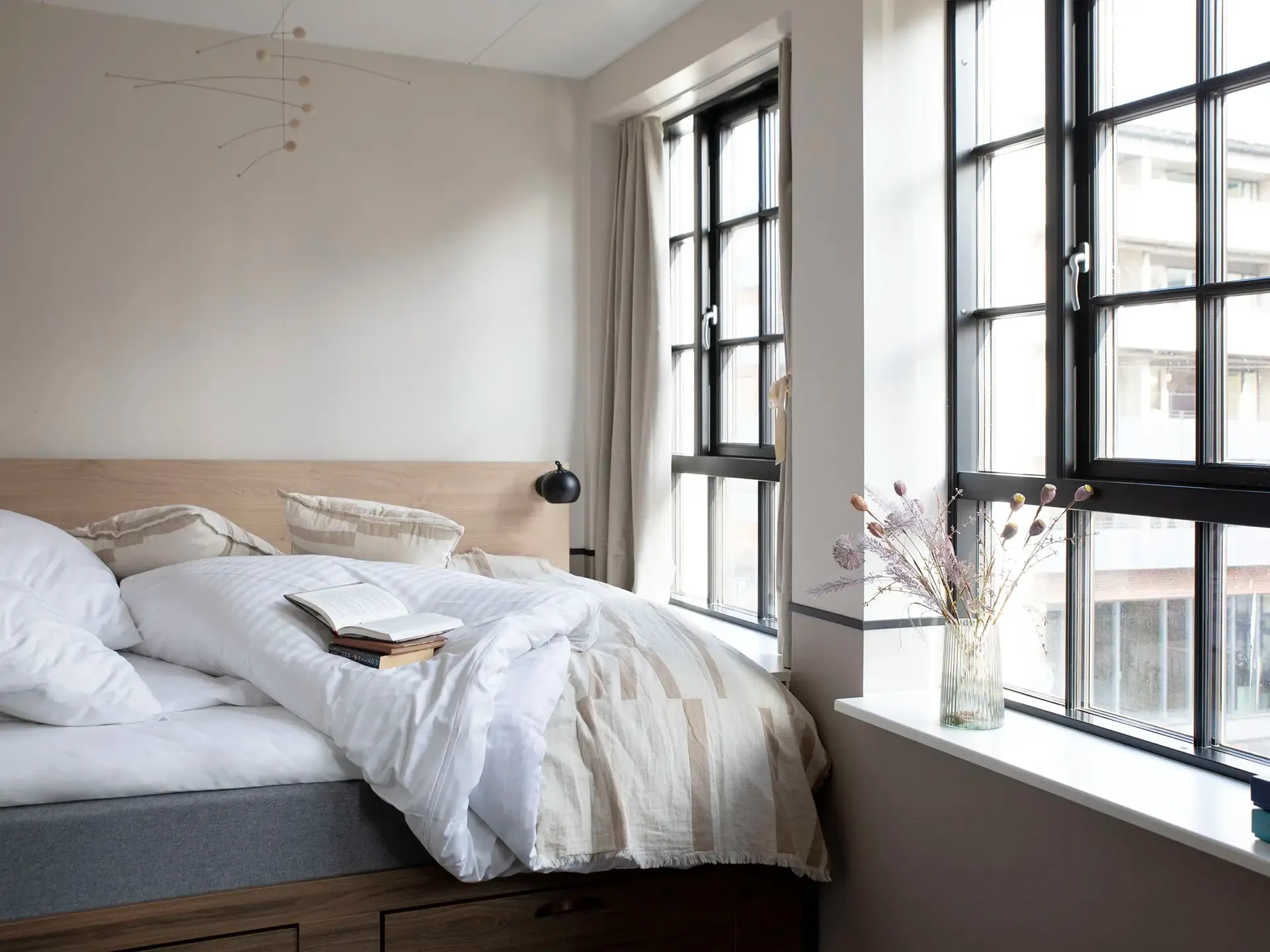 Scandinavian-style hotel room with soft tones and custom-made bed with storage, exemplifying space-saving solutions for hotel projects.