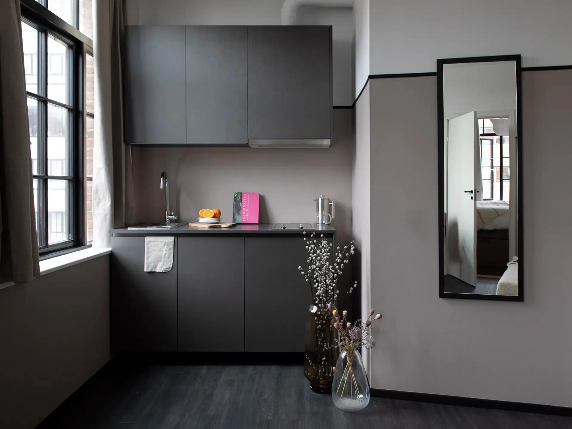 Stylish hotel flat kitchen in soft dark earth tones, designed for compact hospitality units where functionality meets aesthetics.